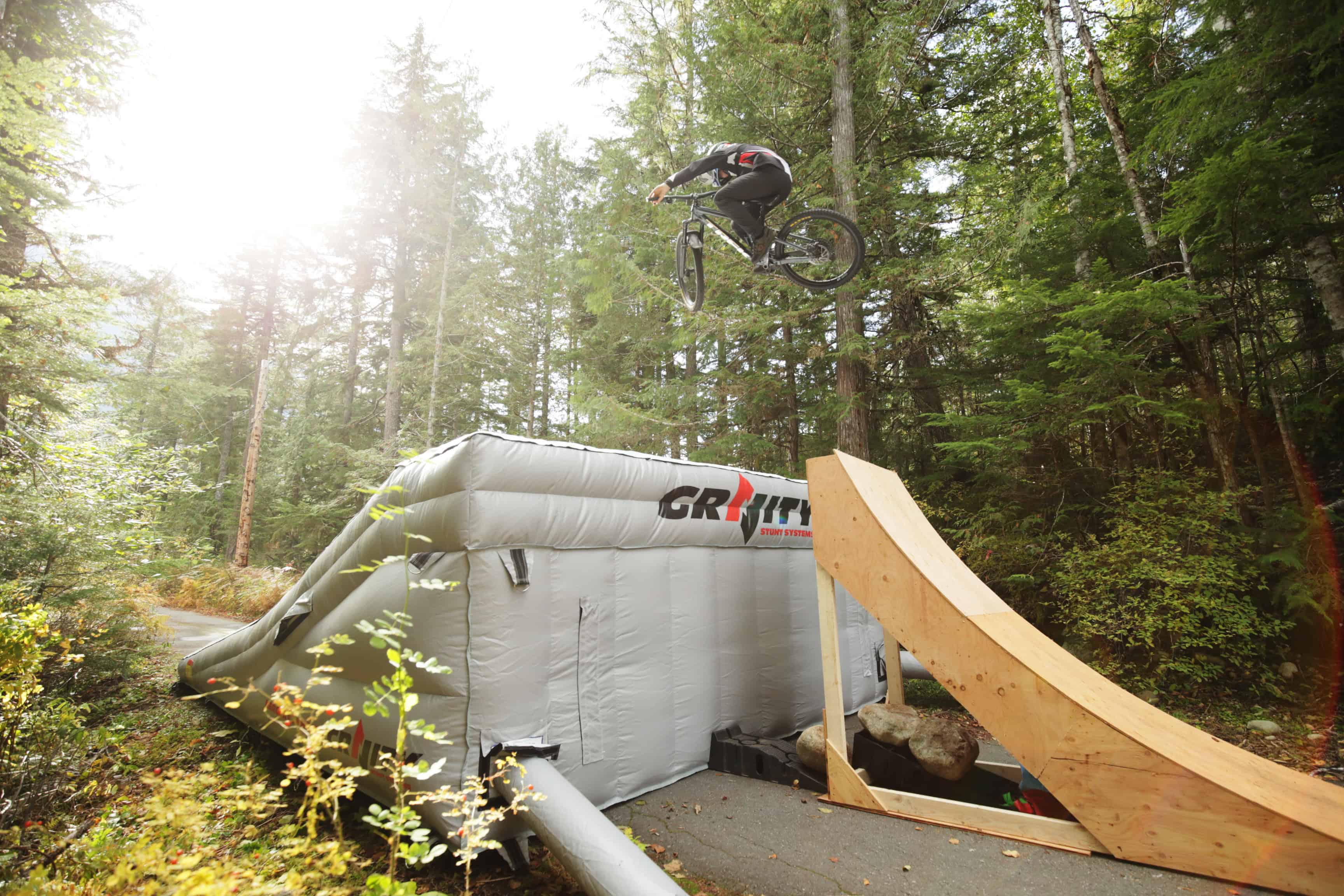 A mountain biker jumps off a Gravity Stunt built ramp showing the back view of the Mercury Lander