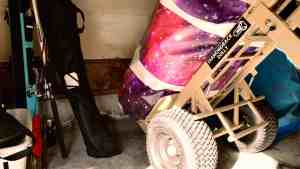 Heavy-duty Diamondback Dolly moving a rolled-up, space-themed purple and pink Gravity Stunts airbag inside a storage garage