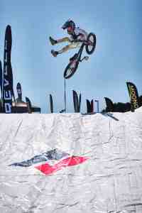 Young mountain biker executing an extended no-foot can-can jump trick above a large airbag landing system during the Sea Otter Classic