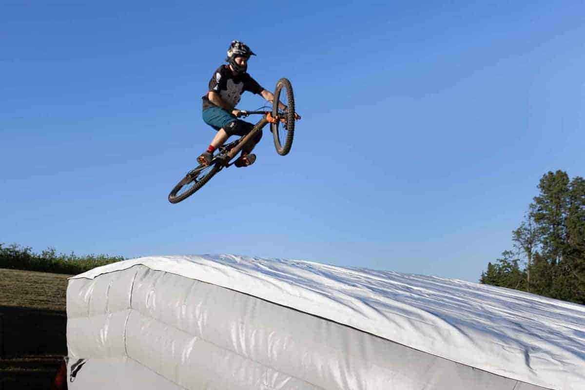 A Mercury lander in use with a biker jumping over it during some backyard mountain bike jumps